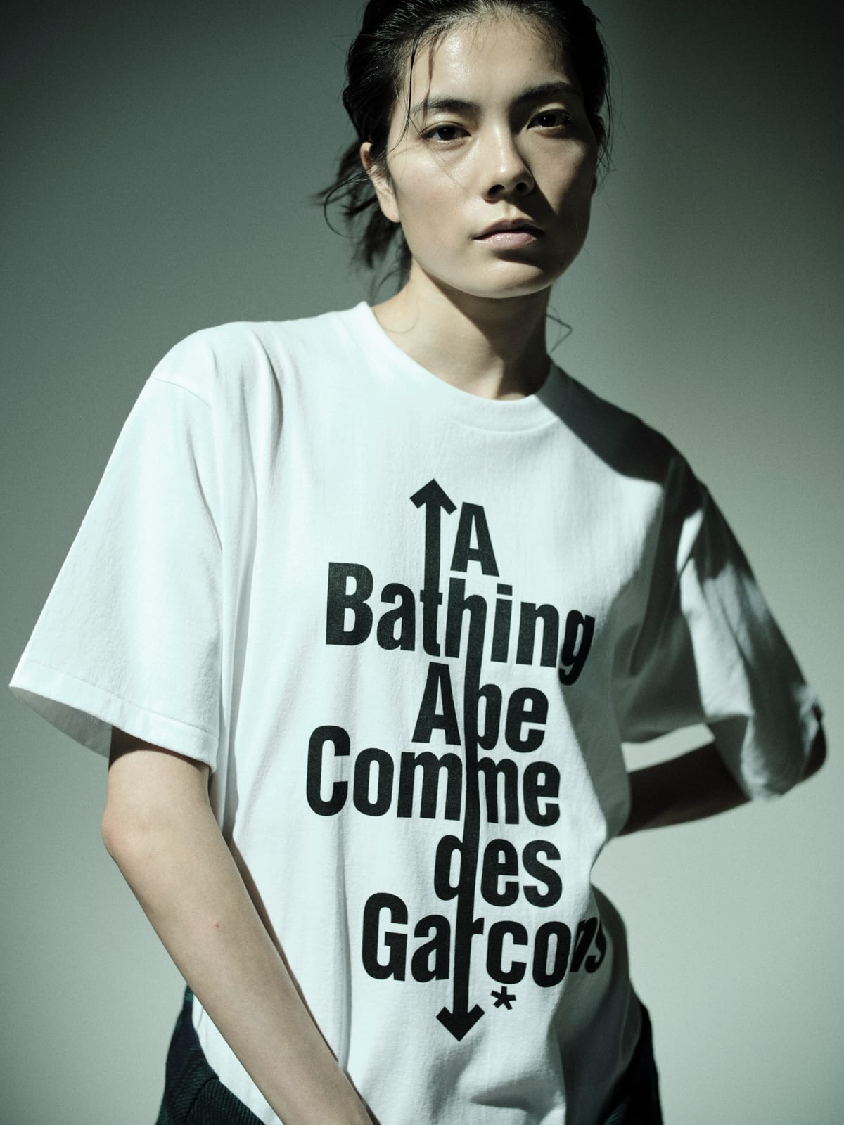 The white CDG OSAKA X BAPE logo tee, with A Bathing Ape and Comme des Garçons stacked vertically through a black arrow