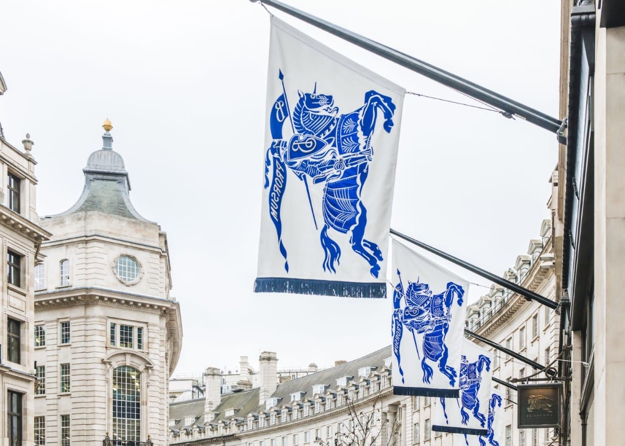 White flags printed with Burberry's blue Equestrian Knight hang from the front of its Regent Street flagship in London, above the shop's hanging Burberry sign