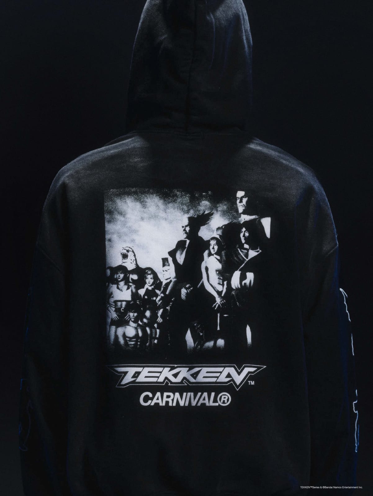The back of the black Carnival x Tekken hoodie, with a black and white photo of the Tekken cast above the TEKKEN and CARNIVAL logos
