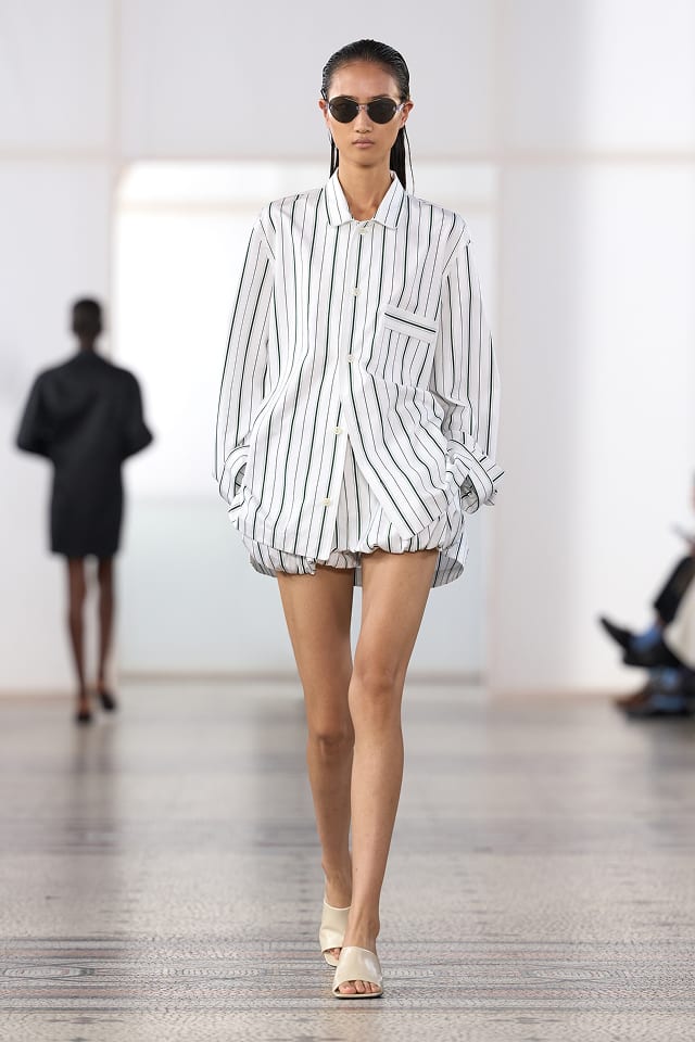 A model in an oversized white shirt with dark stripes over gathered shorts, in Carven's Spring 2027 show