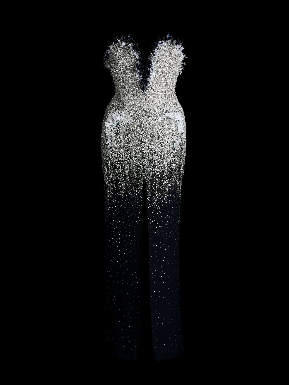 Céline Dion's Chanel Haute Couture dress shown on its own against black: a strapless column with a feathered sweetheart neckline, the bodice thick with silver crystal embroidery that thins out into dark blue down the skirt