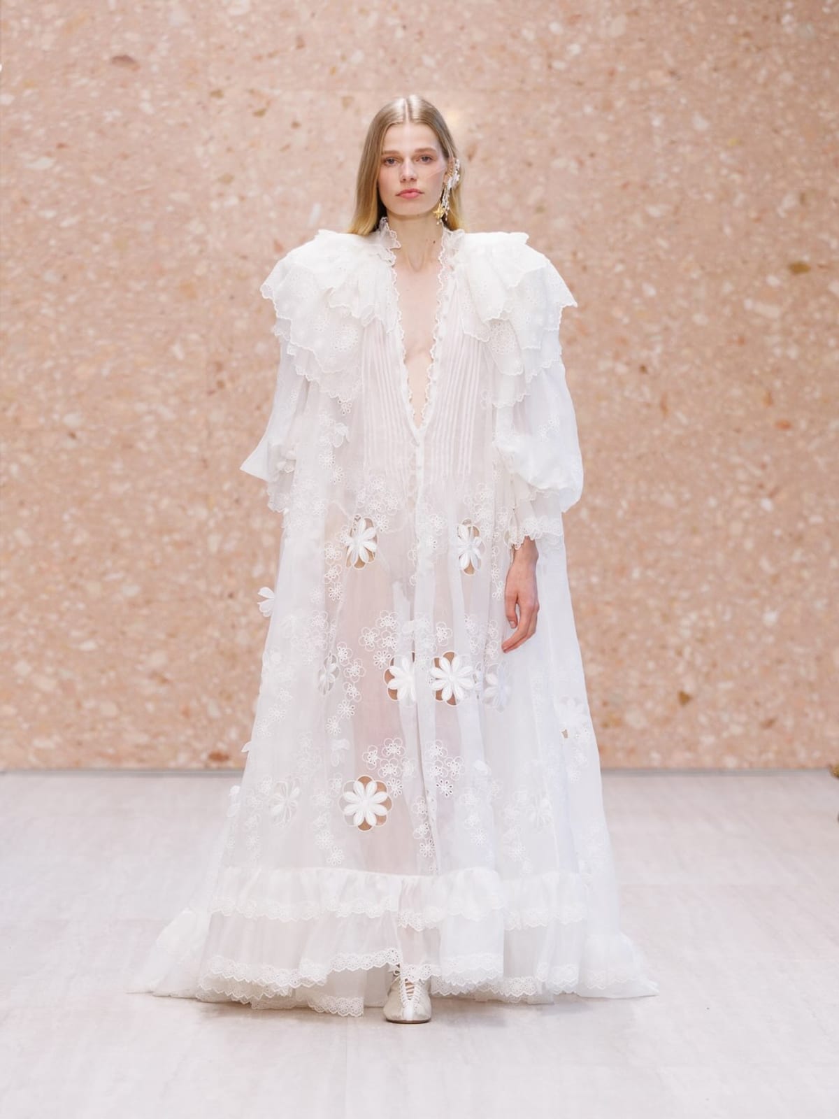 A Chloé Spring/Summer 2027 look: a sheer white ruffled cape-coat scattered with white flowers over a white plunging dress