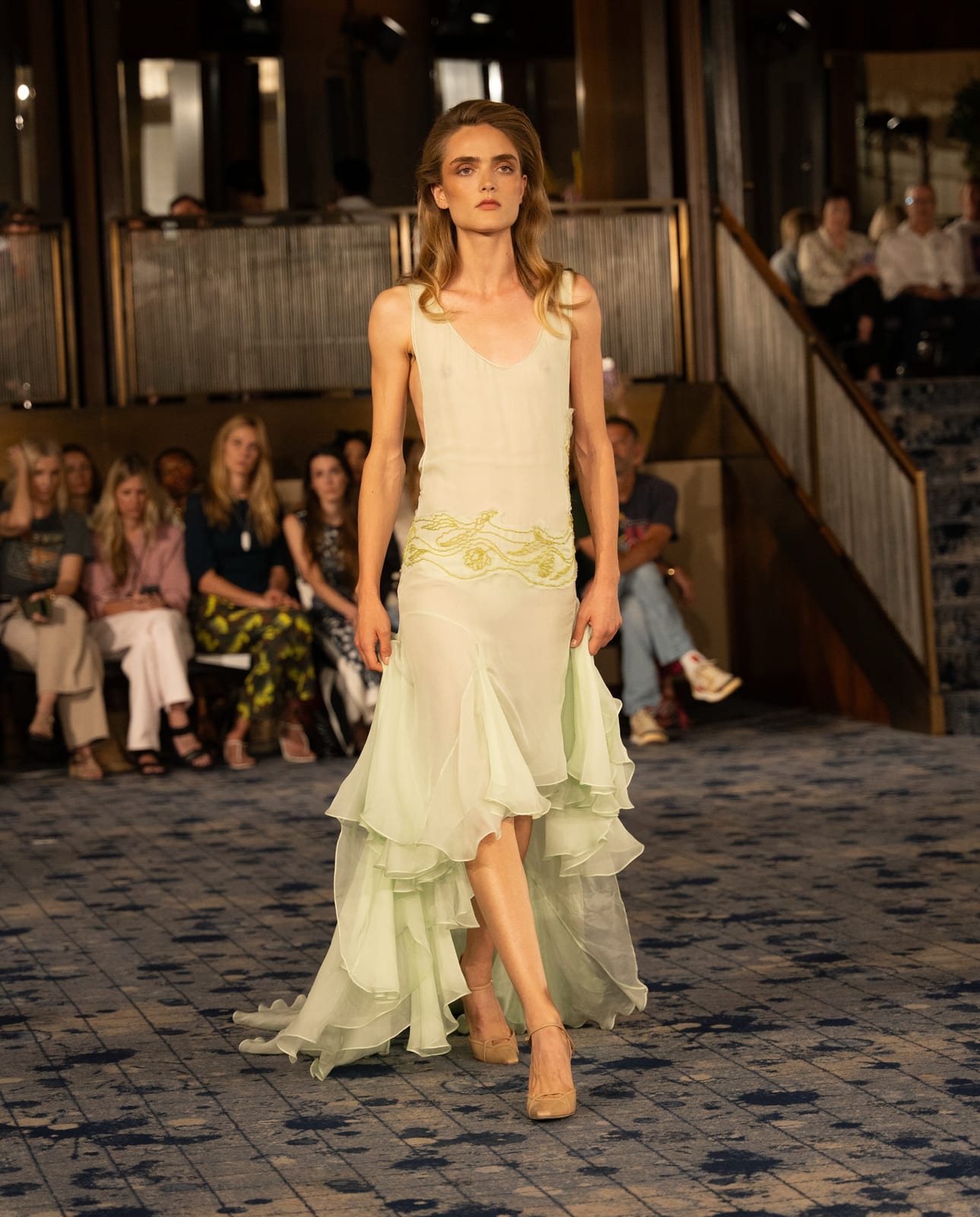The finale Lady Liberty gown from Conner Ives Spring 2027: sheer mint-green chiffon with gold embroidery at the hip and a tiered, trailing ruffle hem