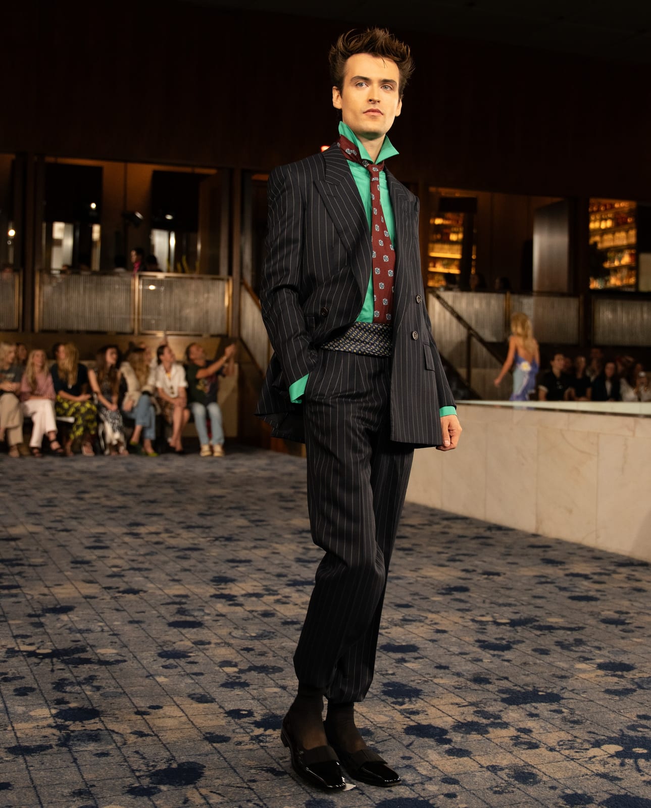 Look 40 from Conner Ives Spring 2027: a bespoke pinstripe suit made with Gieves & Hawkes, worn with a teal shirt, a printed tie and a patterned cummerbund