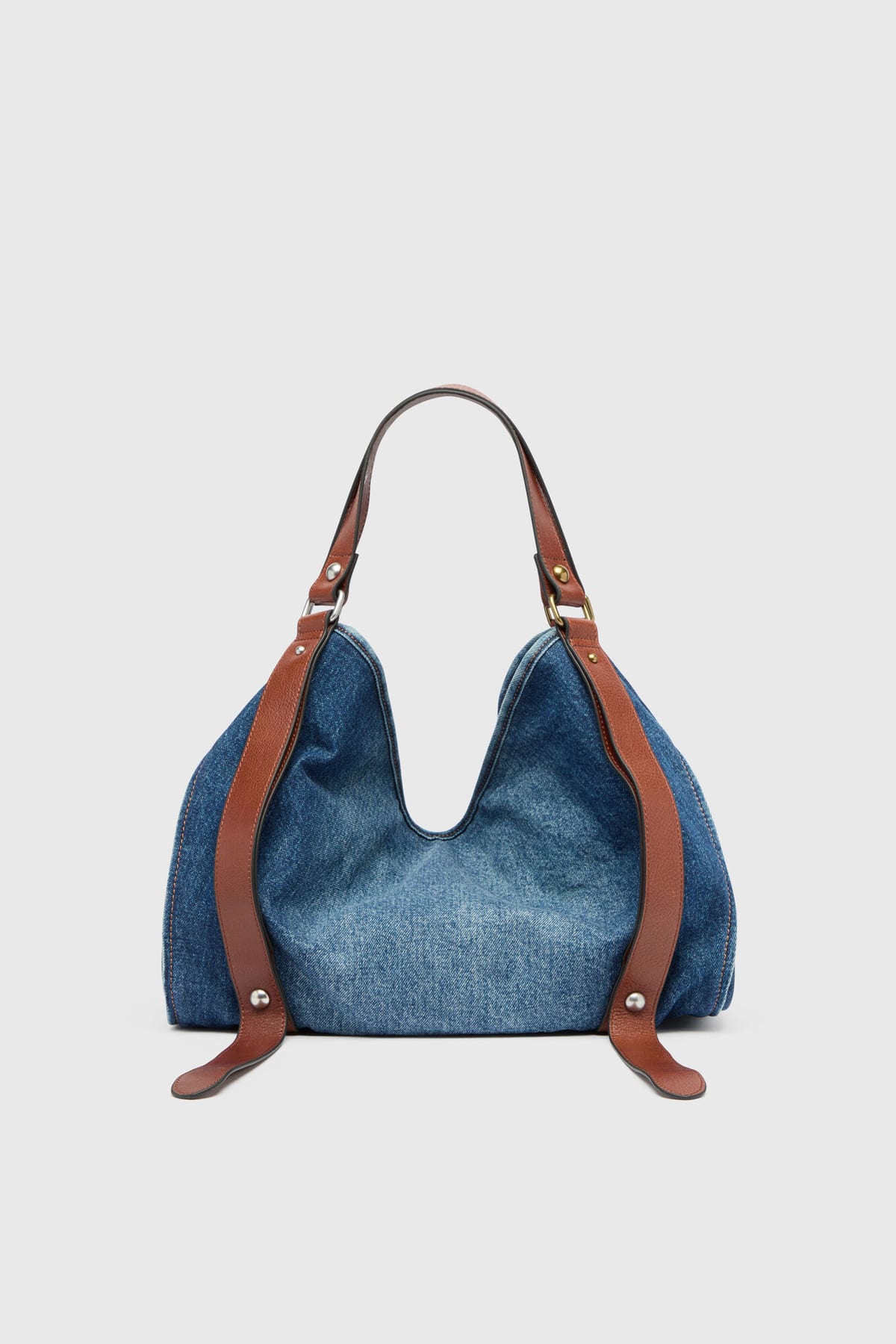 The Diesel D-One Medium top-handle bag in blue denim and leather, a slouchy hobo shape with brown leather straps fixed to the sides and a single arched handle