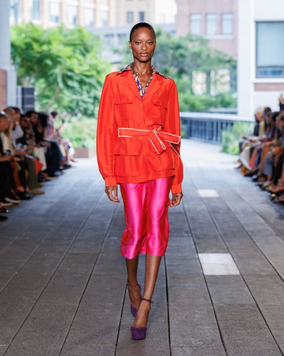 A model in an orange belted utility jacket and a bright pink satin skirt on the Diane von Furstenberg Spring 2027 runway
