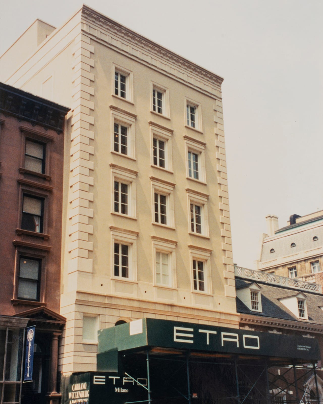 An archive photo of a five-storey pale stone building with rows of tall windows, a dark green construction canopy on scaffolding reading ETRO across the ground floor, and an ETRO Milano sign on the hoarding below