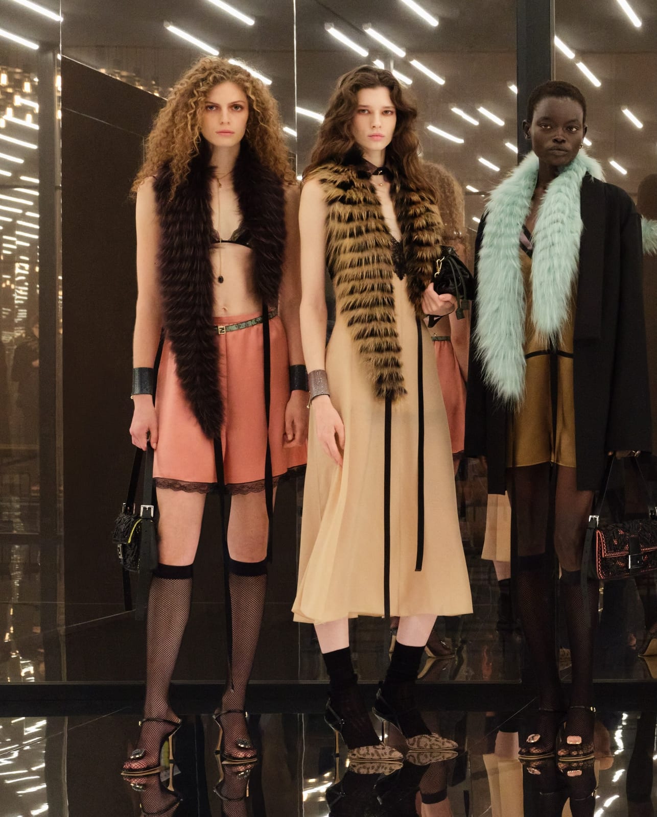 Fendi Spring 2027 looks with long fur stoles worn over a bra and coral shorts, a pale slip dress, and a mint stole with a black skirt