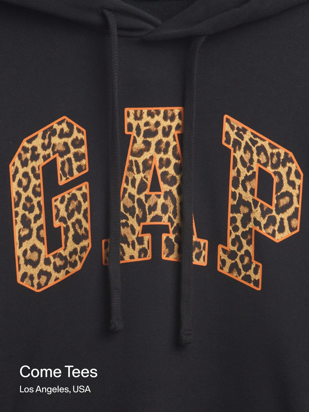 Close-up of a black hoodie with the GAP arch logo filled in leopard print and outlined in orange, white drawcords hanging over it