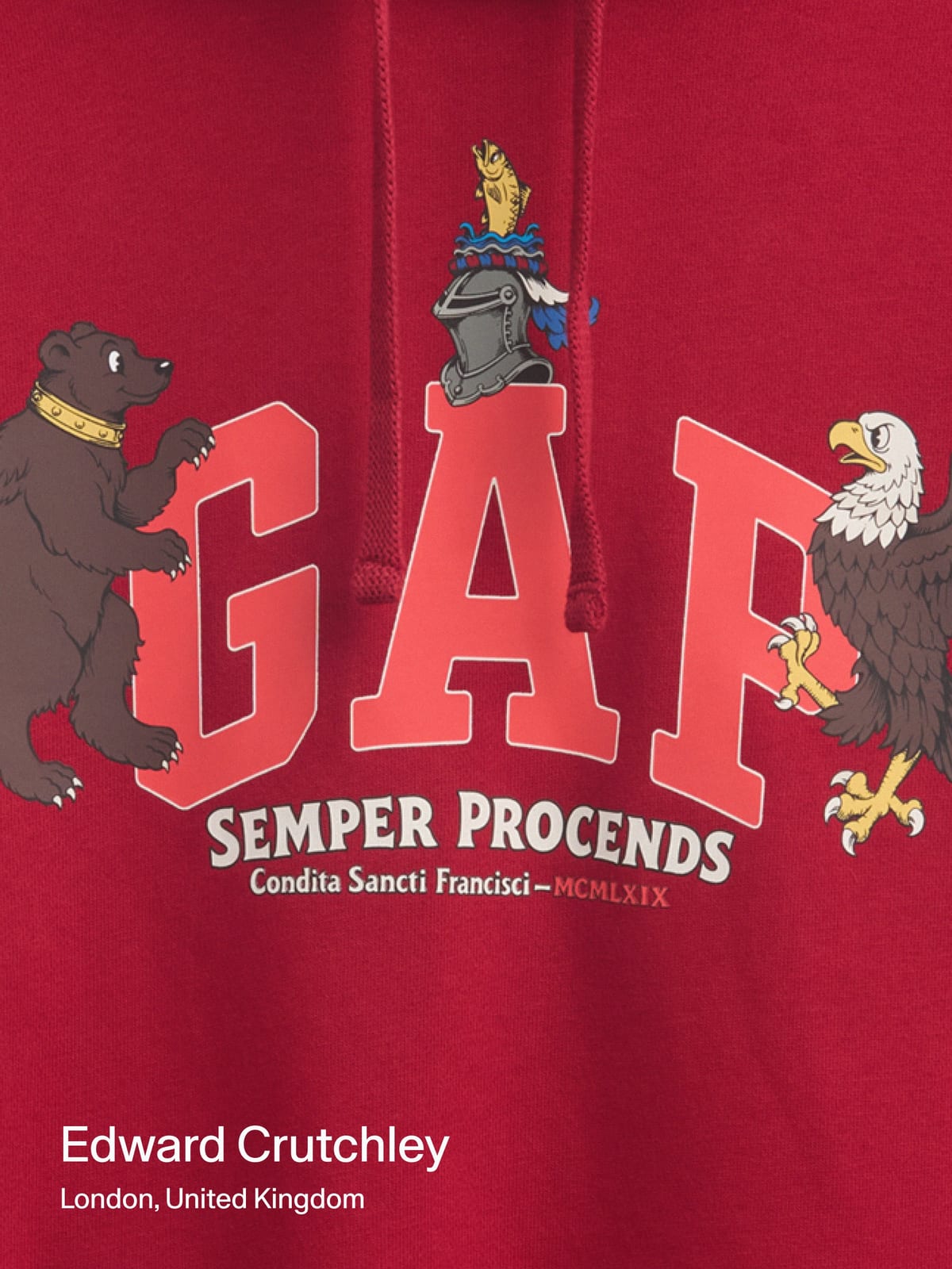 Close-up of a red hoodie printed with a coral GAP between a brown bear and an eagle, with a knight's helmet above and a Latin motto and MCMLXIX in an arc below