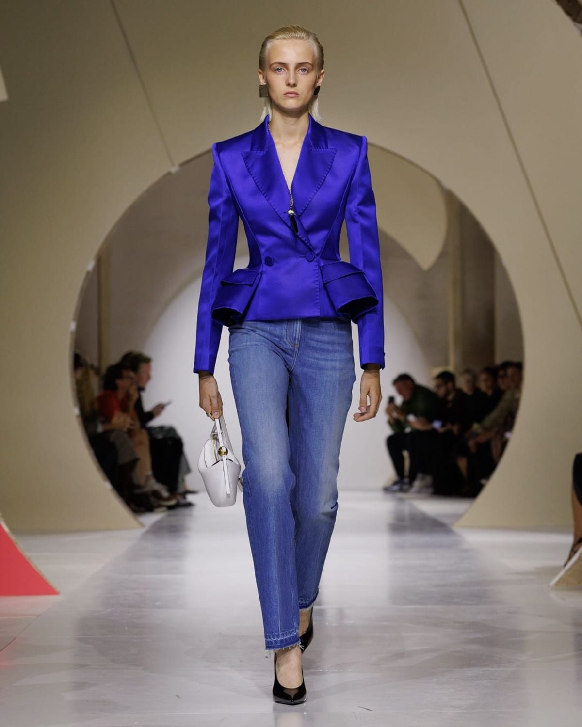 A model on Givenchy's runway in a cobalt blue satin peplum jacket over blue jeans and heels