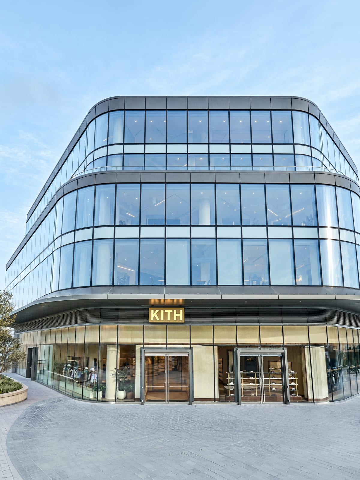 The exterior of Kith Vancouver at Oakridge Park: a curved glass building with a Kith sign over the ground-floor entrance