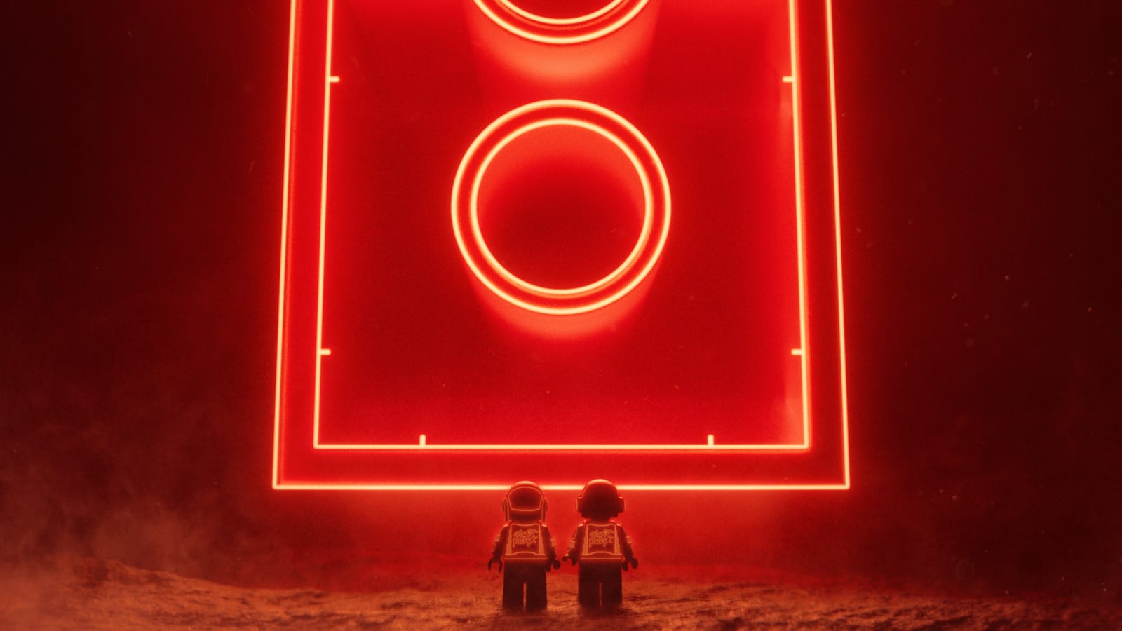 Two small Daft Punk minifigures, seen from behind, stand on dusty ground before a giant red neon outline of a LEGO brick with two glowing circles