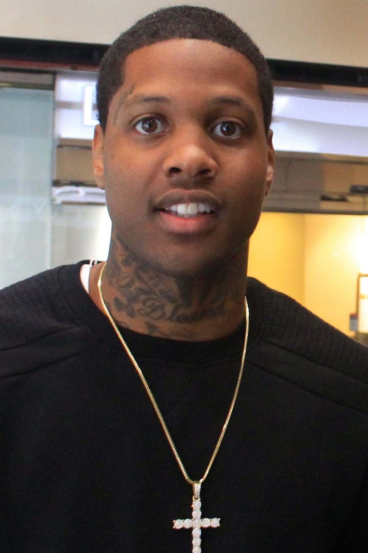 Lil Durk in a black crewneck sweater and a gold chain with a diamond cross pendant, looking at the camera, in 2015