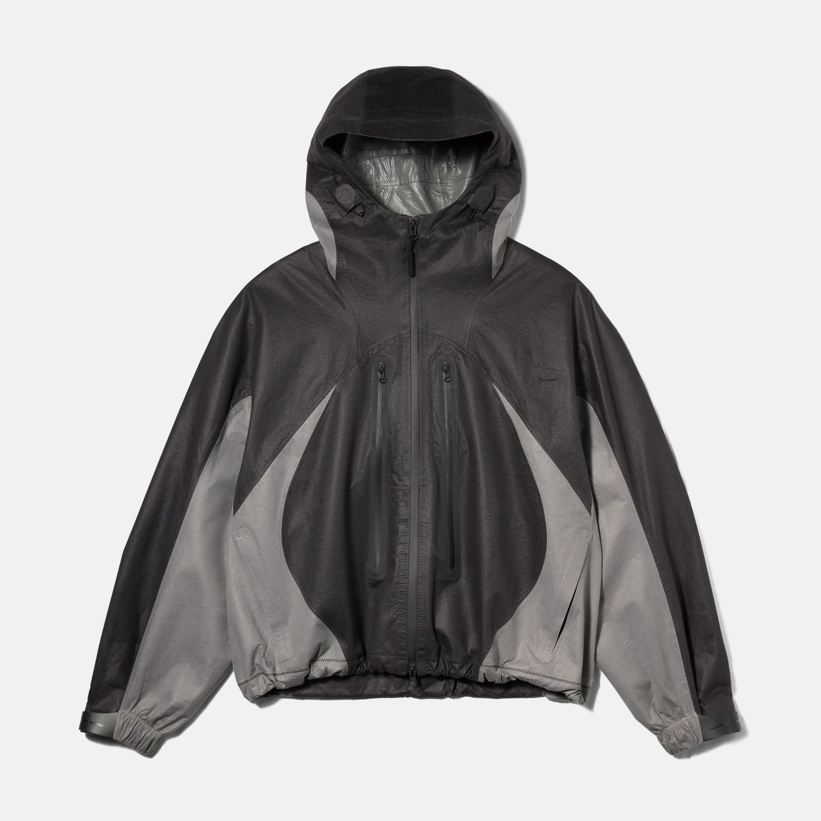 The Nike Tech SF3 jacket laid flat on a white background: a dark charcoal hooded shell with curved light grey panels down the sides and sleeves, two vertical chest zips and a gathered hem