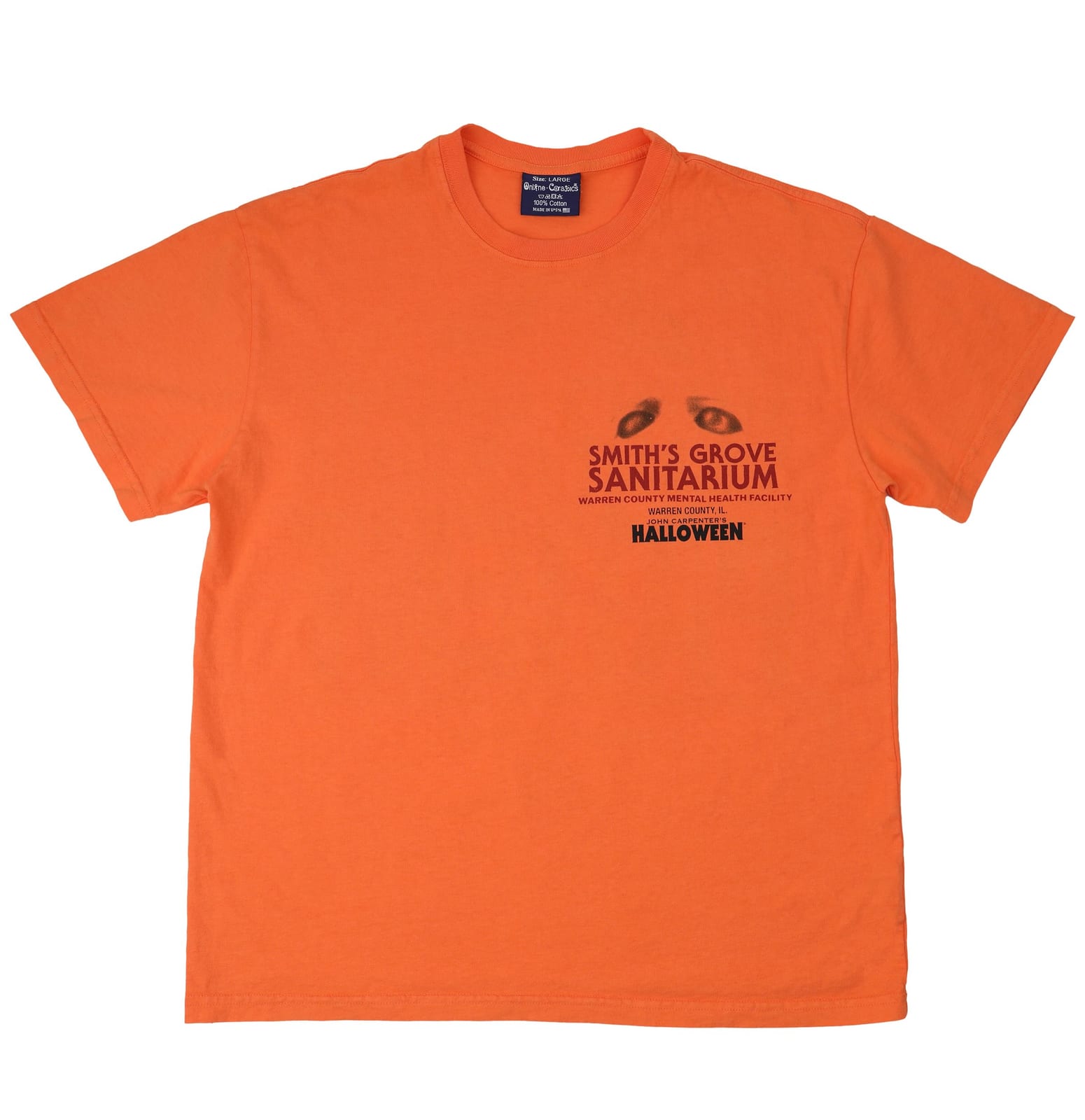 An orange tee with a small chest print reading Smith's Grove Sanitarium, Warren County Mental Health Facility, under a pair of eyes, with the Halloween title below
