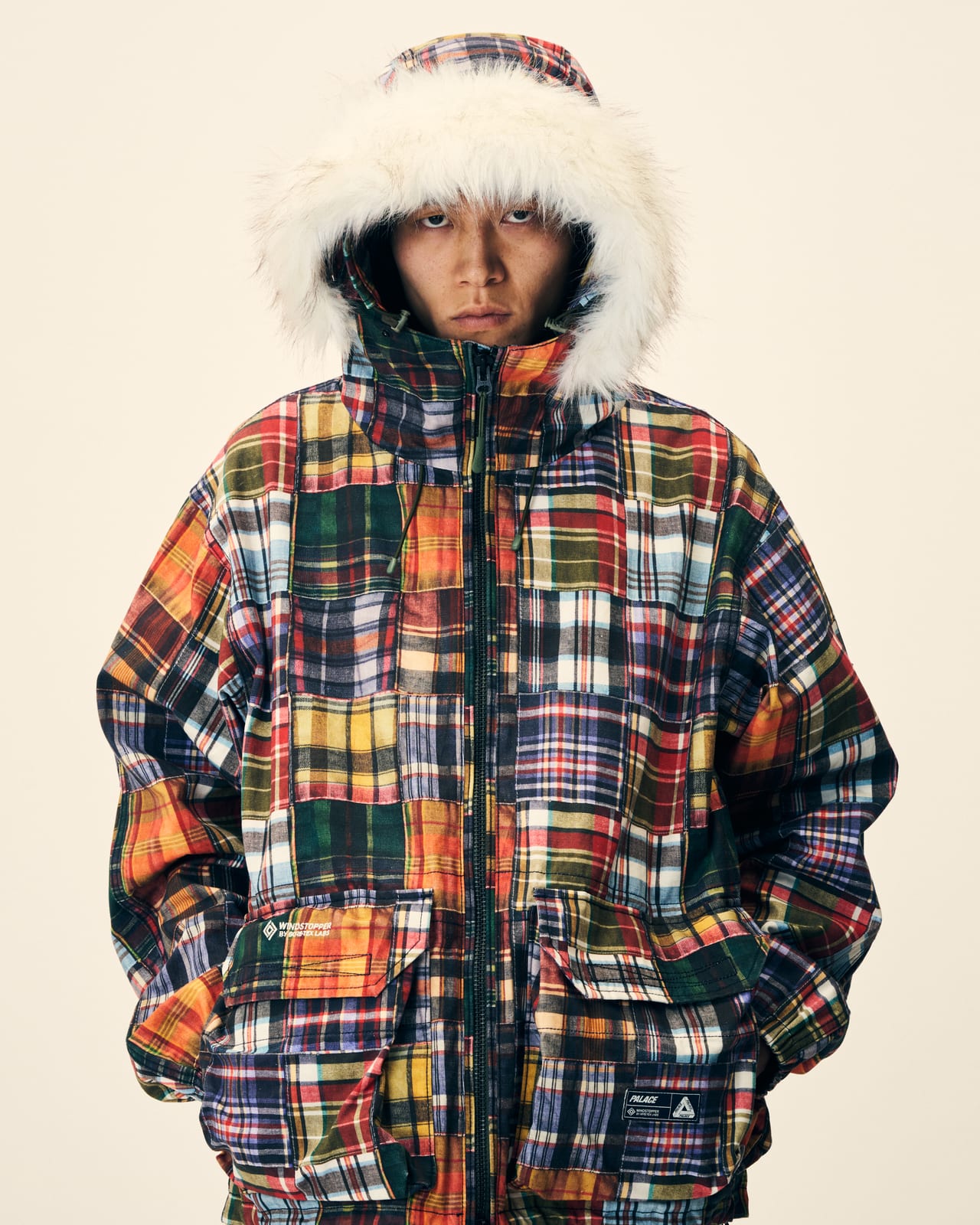 A model in Palace's Winter 2026 patchwork plaid parka with a shaggy trimmed hood, from the Winter 2026 lookbook