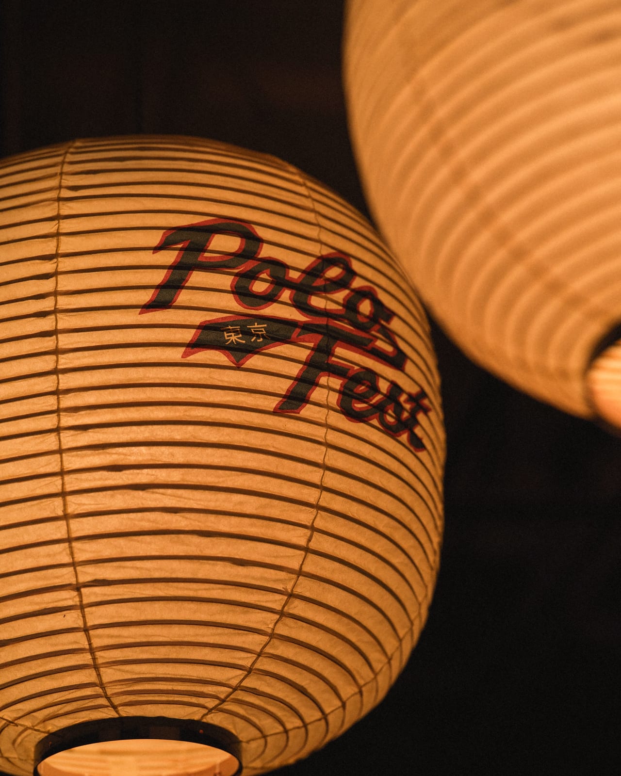 Paper lanterns lit from inside, one printed with the PoloFest script logo