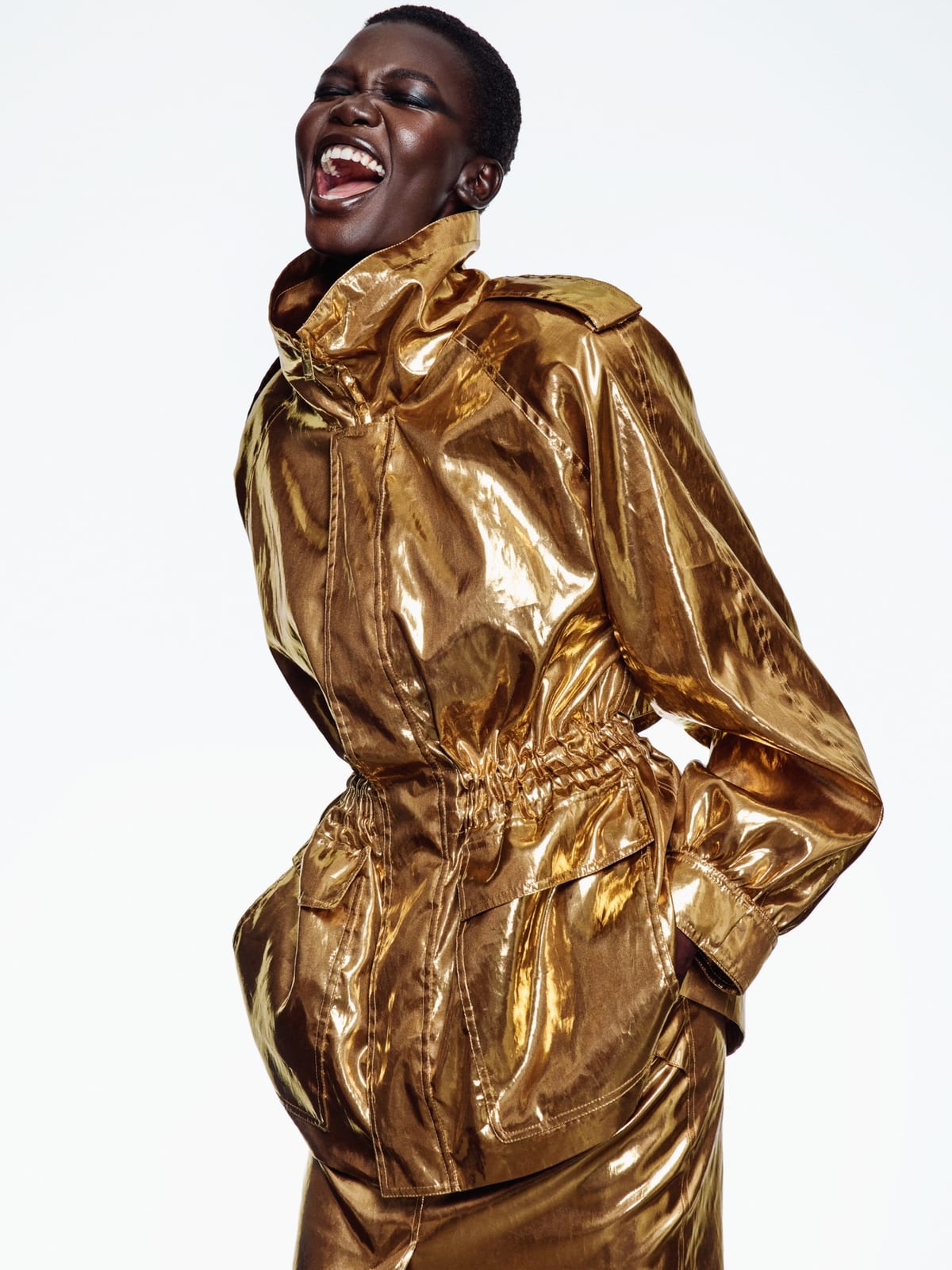 A Saint Laurent Spring/Summer 2027 look: a shiny gold safari jacket with epaulettes and a drawstring waist, over matching gold trousers
