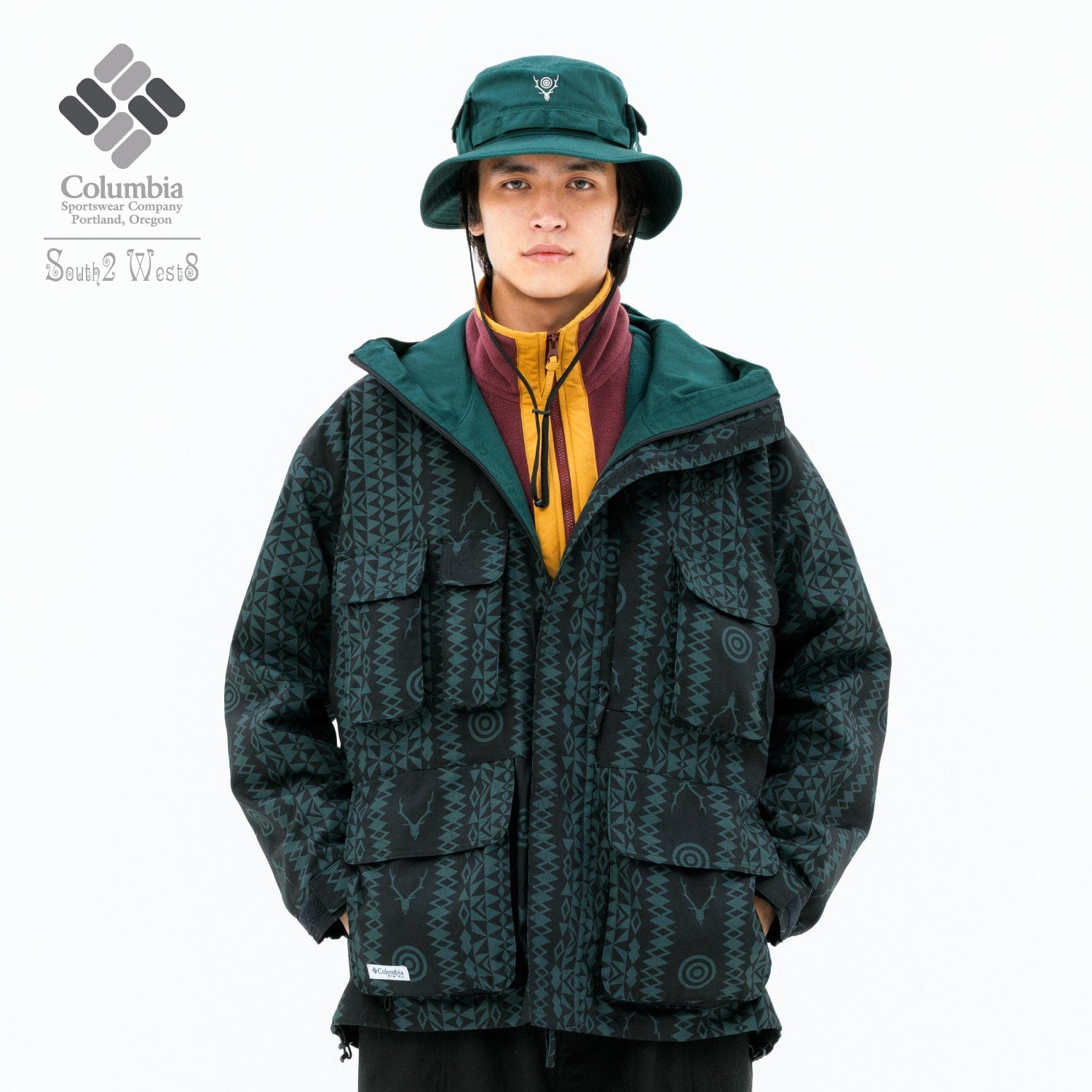A model in a green booney hat and a dark green hooded jacket with a tonal pattern, under a Columbia and South2 West8 lockup
