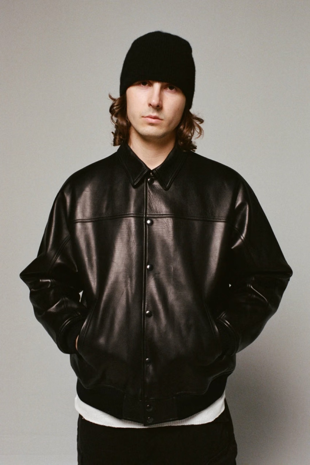 A model in the all-black calfskin leather jacket from Supreme x A.PRESSE and a black beanie