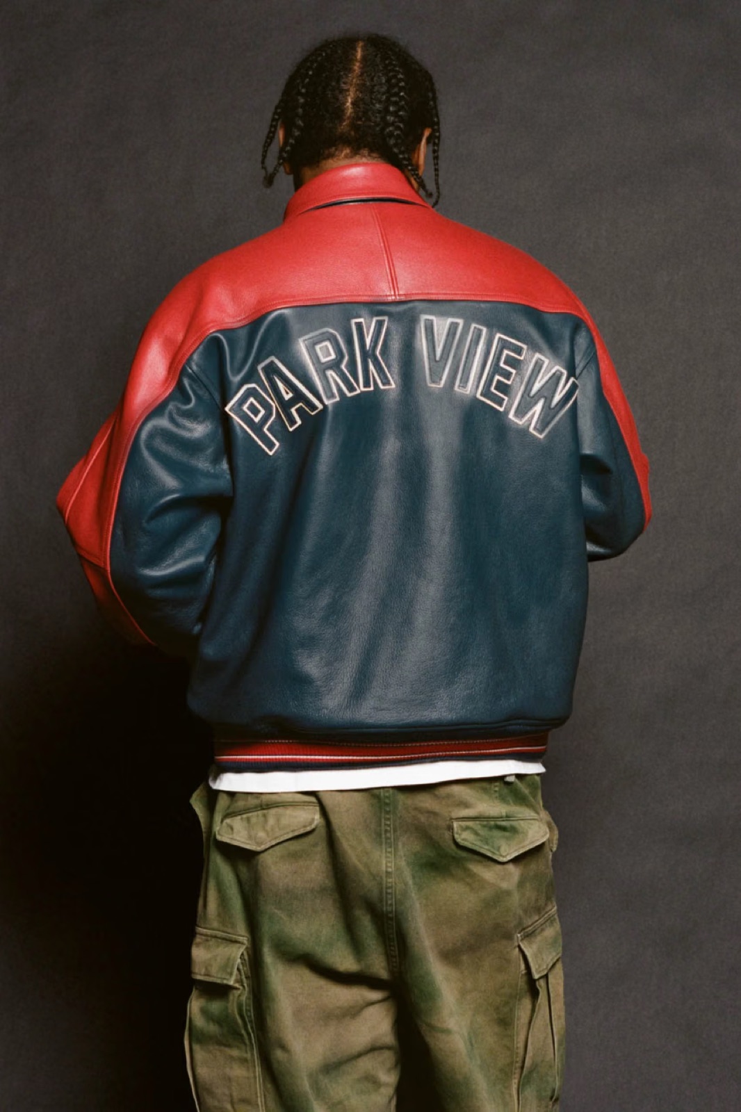 The back of the red and navy cowhide leather jacket with PARK VIEW lettering, worn with camo cargo pants