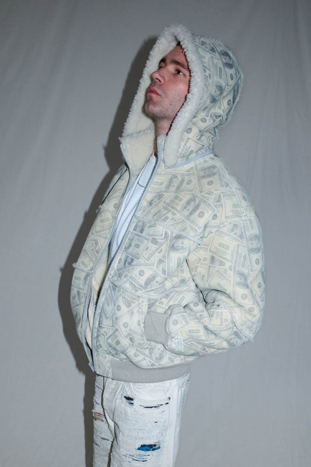 The hooded shearling bomber jacket from Supreme x MM6 Maison Margiela in an all-over $100 bill print, worn over distressed white jeans